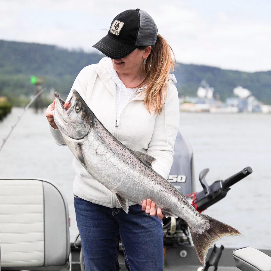 Woman holds spring chinook salmon caught on the Columbia River near Clatskanie and Westport, Oregon with a fishing guide