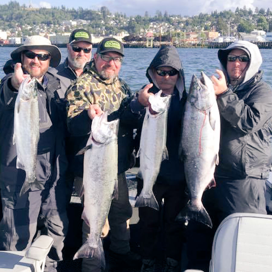 Corporate group holds their salmon up they caught with an Oregon fishing guide for Buoy 10 in Astoria
