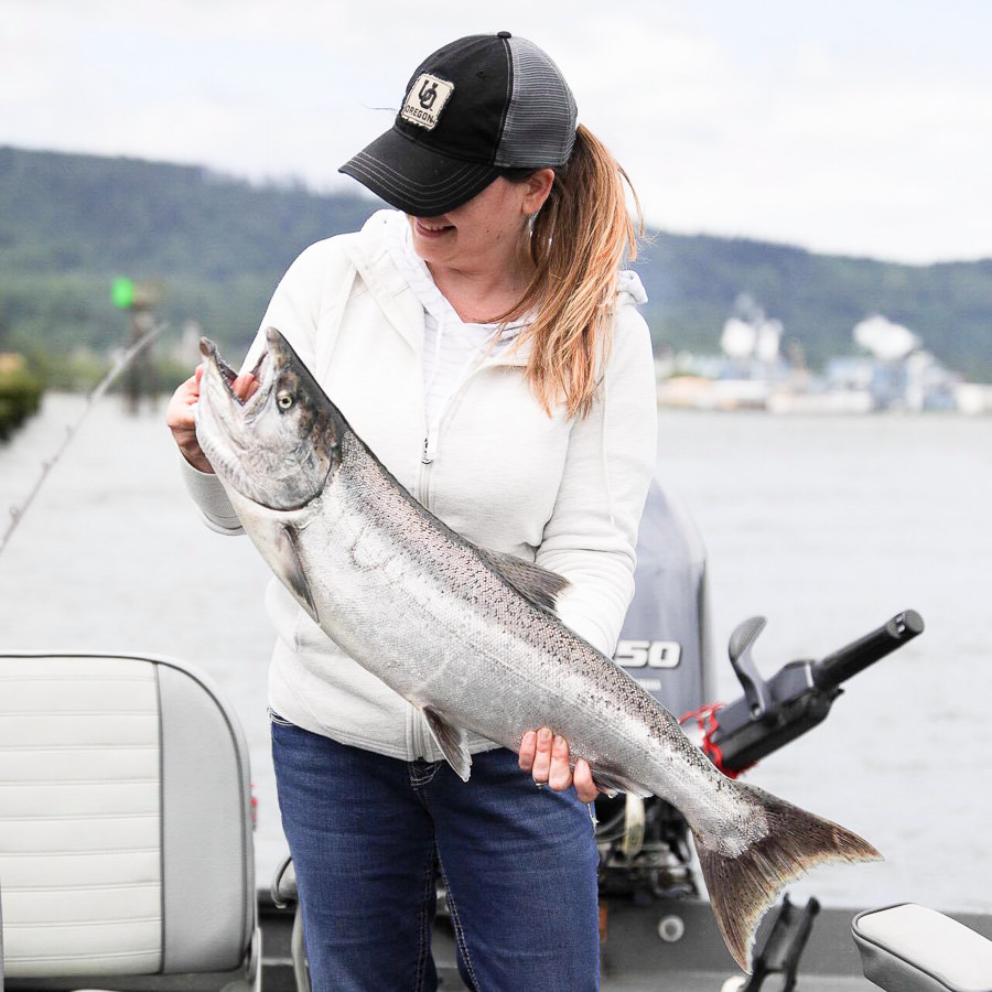 Woman holds a fish caught by a spring chinook salmon fishing guide on the Columbia River in Oregon