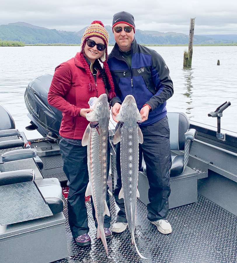 Couple holds up two Sturgeon caught with fishing guide Mike Hazen of Hazen's Guide Service