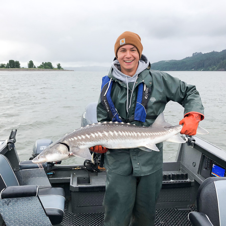 Teen boy holds a sturgeon he caught on the Columbia river on a guided fishing trip near Astoria Oregon