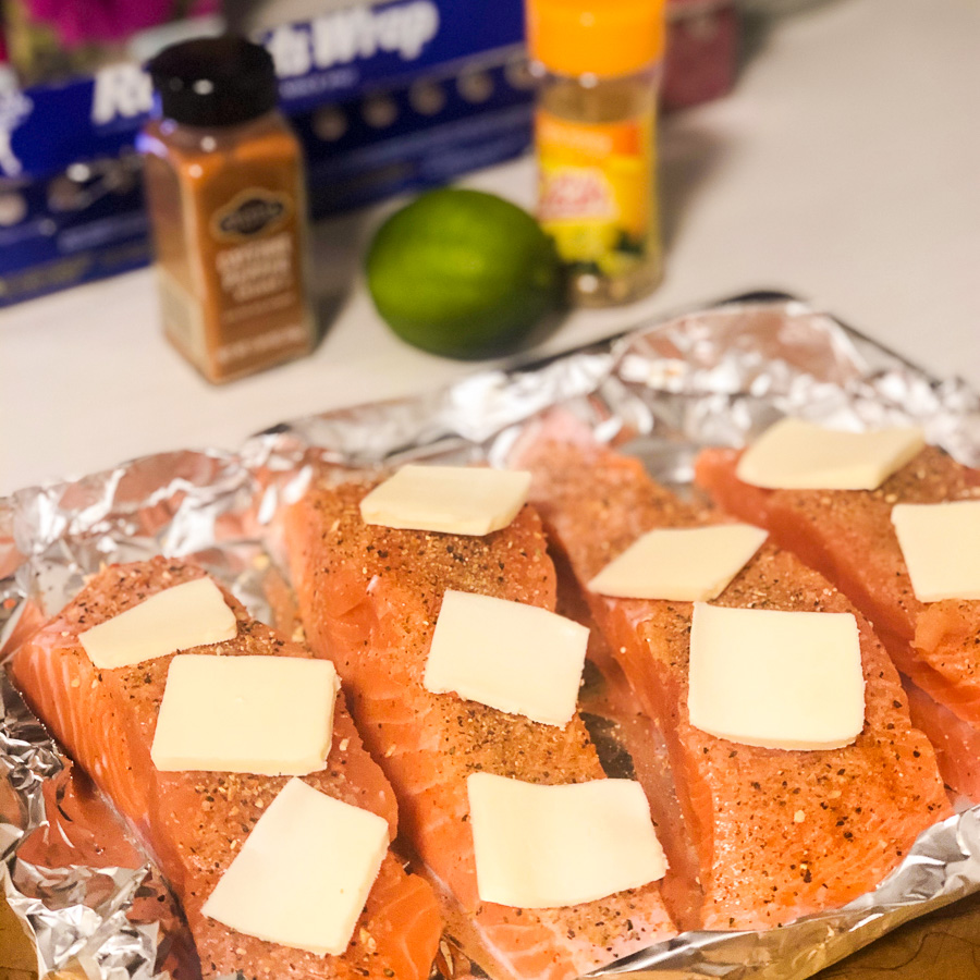 Lemon pepper salmon sits on foil tray ready to cook on the grill. Recipe for cooking your catch from fishing.