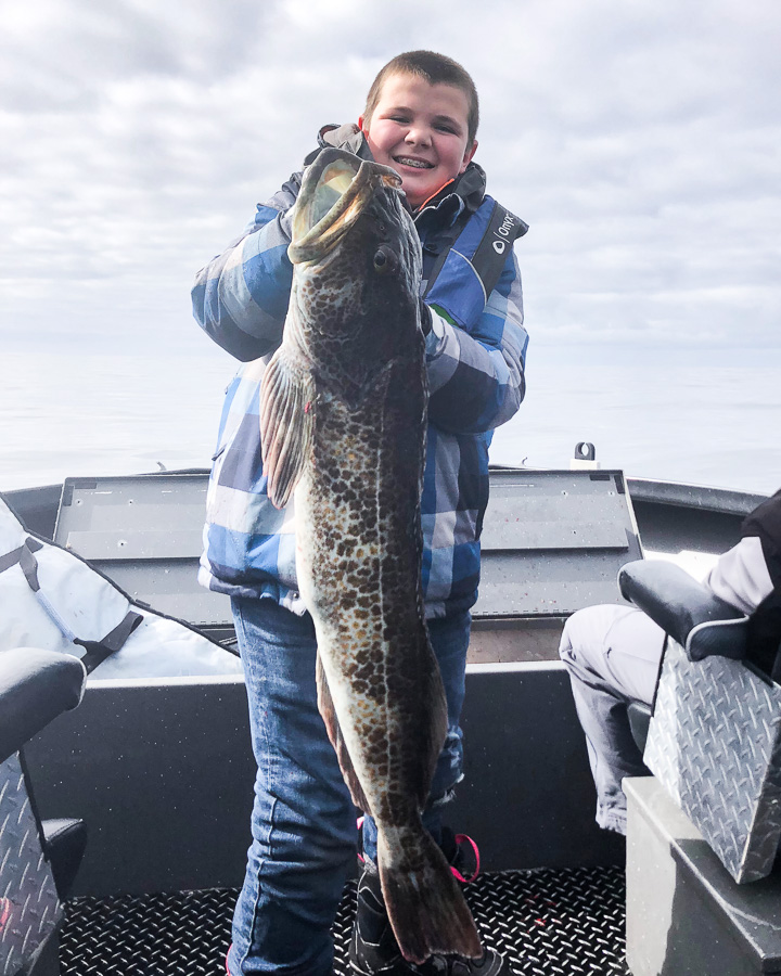 Boy holds up huge Lingcod caught on a charter fishing trip near Tillamook, Oregon and Garibaldi