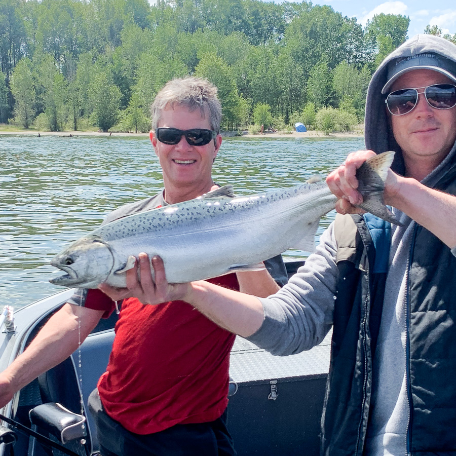 Fishing guide Mike Hazen poses for a photo with a happy client while holding up a Columbia river spring chinook salmon