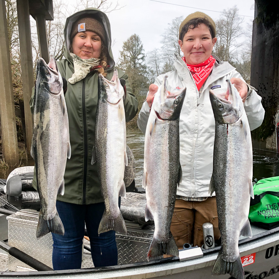 Two women hold up winter steelhead they caught on a guided fishing trip on the Wilson River out of Tillamook, Oregon with Guide Mike Hazen