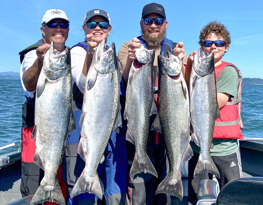 Four people hold up 5 large salmon caught at Buoy 10 in Astoria