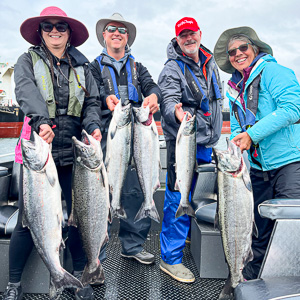 Group of four hold up the fish they caught on the Columbia River for the buoy 10 season with fishing guide Mike Hazen